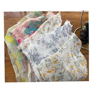 Primo piano di vari foulard triangolari in lino a fiori su un tavolo di legno rustico