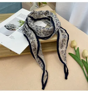 Vista detallada de un elegante pañuelo de seda con estampado floral y borde azul marino en madera