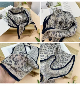 Vista detallada de un pañuelo beige con motivos florales azul marino y dobladillo.