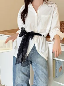 Detail of black polka dot linen scarf tied as a waist belt on a white shirt