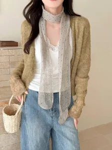 Detailed close-up of a grey linen polka dot skinny scarf styled with a knit cardigan outfit