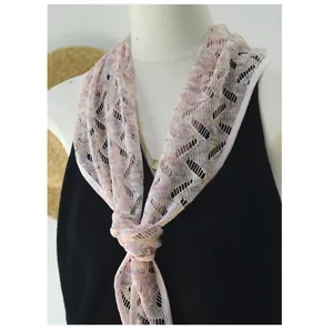Dettaglio di un foulard a triangolo in pizzo floreale annodato sul collo di un manichino