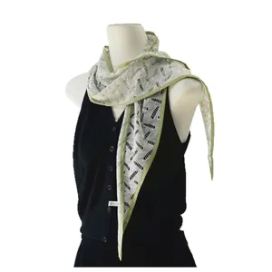 Piccola sciarpa a triangolo in pizzo floreale con bordo verde chiaro su un gilet nero