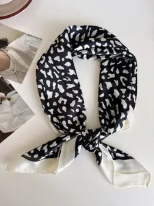 Dettaglio di un foulard di seta a motivi bianco e nero su uno sfondo minimalista.