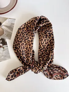 Vista dettagliata del foulard quadrato setoso con stampa leopardata e nodo.