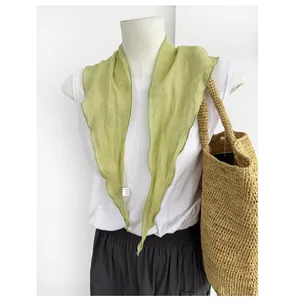 Dettaglio di un foulard a triangolo in puro lino verde chiaro con bordi arrotolati