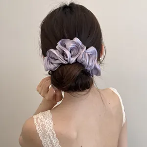 Gedetailleerd overzicht van een elegante paarse satijnen scrunchie op een knot