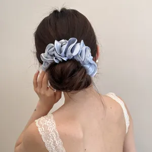 Gedetailleerd aanzicht van een lichtblauw geplooid satijnen scrunchie op een knot