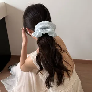 Detailansicht eines sanften hellblauen Scrunchies mit Sternenglanz im dunklen Haar