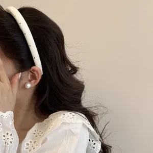 Vue détaillée d'un serre-tête crème à pois porté par un modèle aux cheveux ondulés