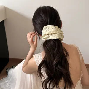 Gedetailleerde weergave van een elegante gele bloemen scrunchie in golvend haar