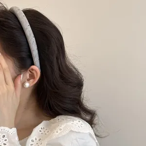Gros plan d'un serre-tête en tissu gris à pois porté avec une boucle d'oreille en perle.