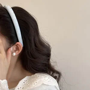 Gros plan d'un serre-tête bleu clair à pois et d'élégantes boucles d'oreilles en perles