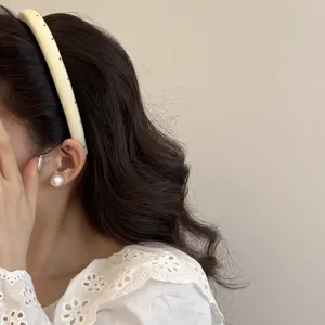 Vue détaillée d'un serre-tête à pois crème porté par un mannequin aux cheveux ondulés