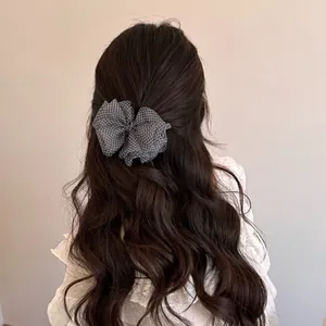Detailed view of a Korean style checkered mesh bow hair clip on long wavy hair