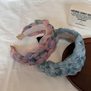 Texture détaillée de deux serre-têtes tressés de rêve en gaze tie-dye, tons rose et bleu