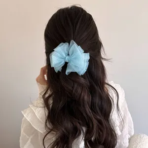 Detail of a light blue mesh bow hair clip on long wavy hair, showing elegant texture.