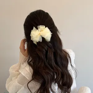 Elegant cream mesh bow hair clip shown on a woman's ponytail from the back view