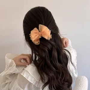 Macro view of an elegant mesh bow hair clip styled on dark wavy hair for daily wear