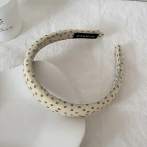 Detailweergave van een gele bloemen hoofdband van gaas met een handgemaakt label.