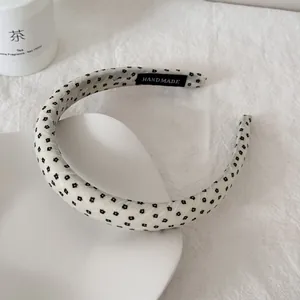 Detailweergave van een witte stoffen hoofdband met zwarte bloemenprint en handgemaakt label.