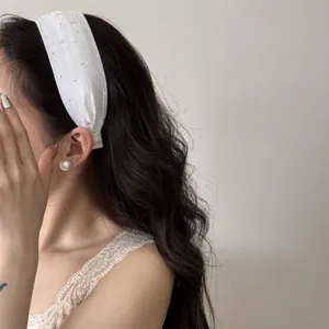 Vue détaillée d'un élégant serre-tête large blanc scintillant sur cheveux ondulés