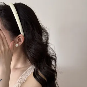 Vue détaillée d'un serre-tête large crème avec motifs d'étoiles sur des cheveux ondulés
