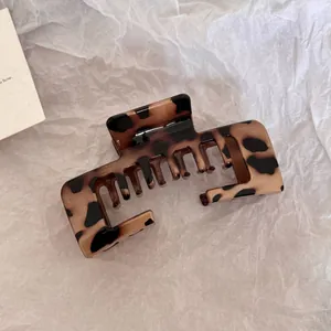 Detailed macro view of a large leopard print hair claw clip on textured white paper background