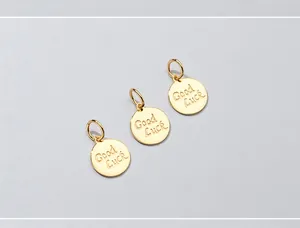Dettaglio di tre ciondoli rotondi in argento S925 placcati oro con scritta Good Luck