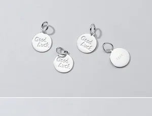 Primo piano di ciondoli tondi in argento S925 con incisione Good Luck per gioielli fai da te