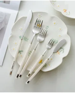Detailed view of a Nordic stainless steel cutlery set with elegant creamy white handles