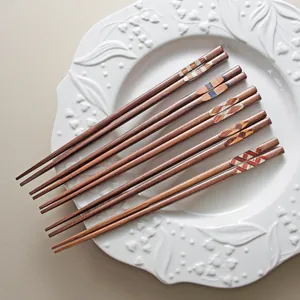 Handcrafted Japanese black walnut wooden chopsticks with assorted patterns on a white plate