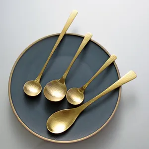 Premium gold hammered stainless steel dessert spoons set displayed on a dark ceramic plate