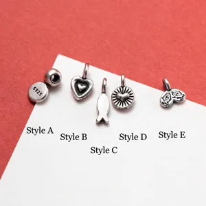 Detailweergave van vijf mini S925 sterling zilveren bedeltjes in hart- en visvormen