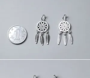 Macro view of S925 silver dreamcatcher charms with a coin for scale reference.