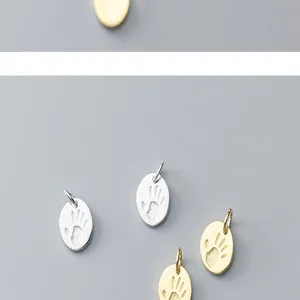 Close-up of S925 silver paw print charms in gold and silver finish for DIY jewelry.