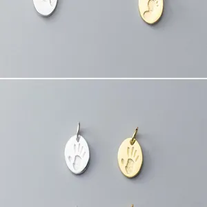 Detailed macro view of S925 silver handprint and footprint charm pendants in silver and gold