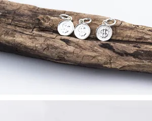 Macro-weergave van drie S925 sterling zilveren dollarteken munt bedeltjes op hout