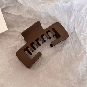 Macro view of a matte brown large rectangular shark hair claw clip on white paper