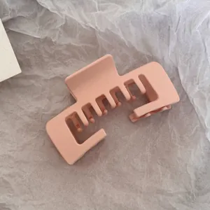 Detailed close-up view of a matte peach rectangular hair claw clip on textured paper.