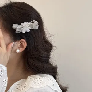 Detalle de una pinza para el pelo con lazo de malla y dije de oso en cabello oscuro