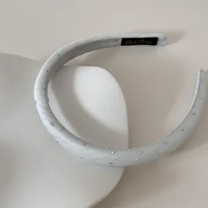 Vue détaillée d'un serre-tête large en tissu blanc avec de fins décors étoilés.