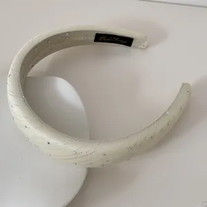 Détail d'un serre-tête rembourré crème avec des motifs délicats d'étoiles argentées.