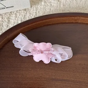 Detalle de una pinza para el pelo rosa con lazo de malla multicapa y adorno de oso