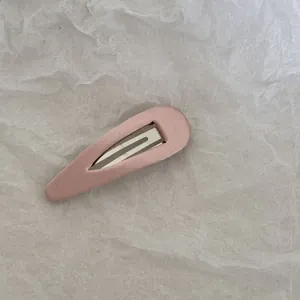 Gros plan d'une barrette à cheveux BB recouverte de tissu rose sur du papier blanc plissé
