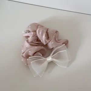 Detail eines rosa Satin-Haargummis mit Herzmuster und weißer Organza-Schleife