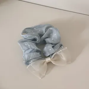 Nahaufnahme des blauen Herz-Haargummis mit einer großen creme Organza-Schleife