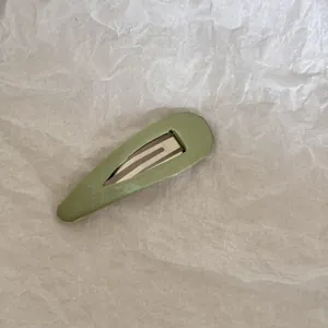 Vue détaillée d'une pince à cheveux en tissu vert sauge sur fond de papier froissé