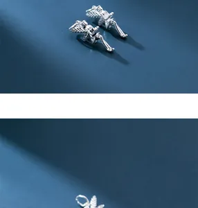 Macro detail of two vintage 925 sterling silver winged angel pendants on blue background