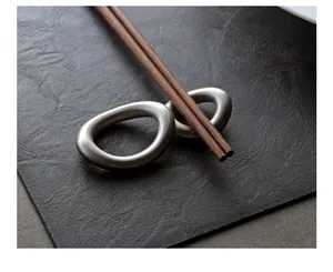 Detailed close-up of matte 304 stainless steel chopstick rest on a dark textured mat